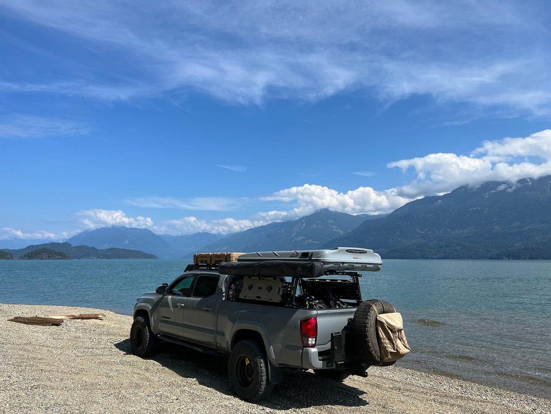 A Toyota pickup with a Peak Offroad bed rack at the river.